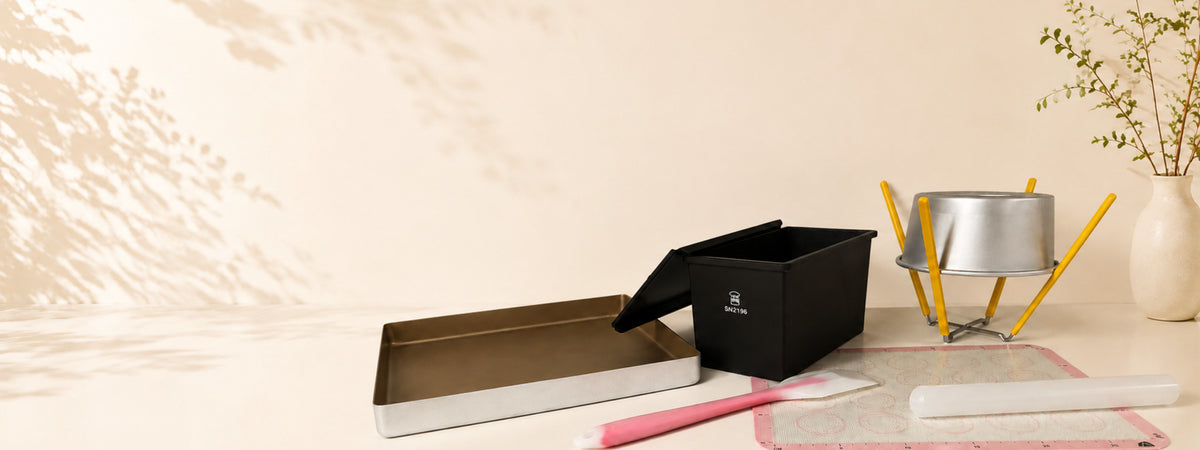 SpicyCookee baking tools arranged on a warm cream surface with soft natural leaf shadows
